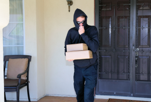 Man in mask stealing package off porch