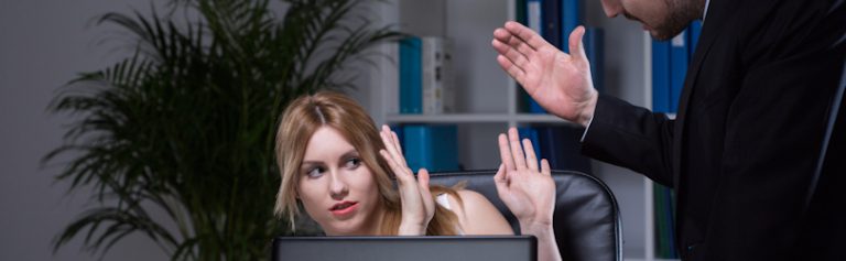 woman sitting at desk about to be slapped by standing male